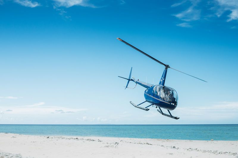 Helicopter flying over a white sand beach